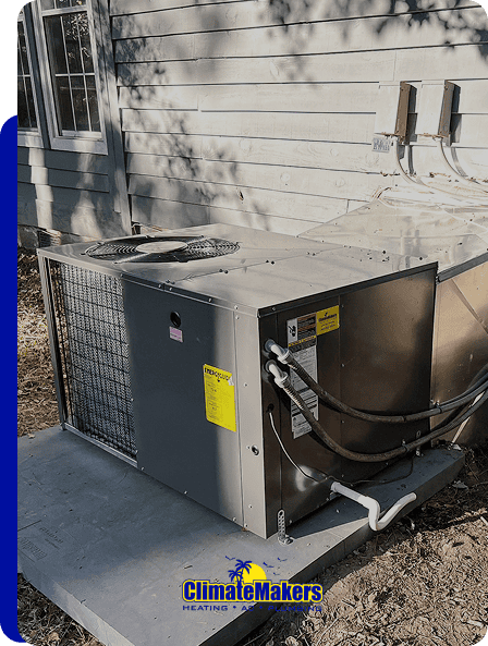 Outdoor HVAC unit installed on a concrete pad beside a house, with visible ductwork and piping. The ClimateMakers logo at the bottom highlights expert installation for reliable home comfort.